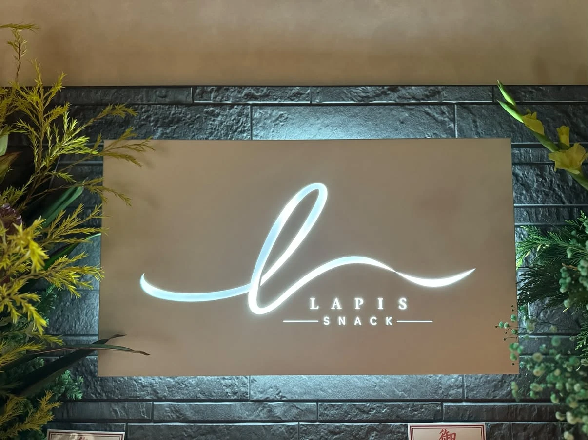 植物に囲まれたLAPIS SNACKの店内看板